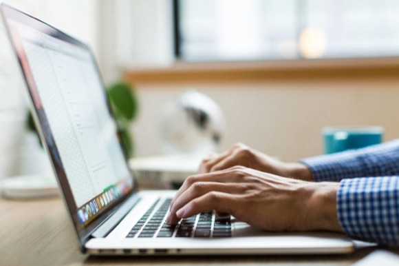 Hands typing on a laptop keyboard